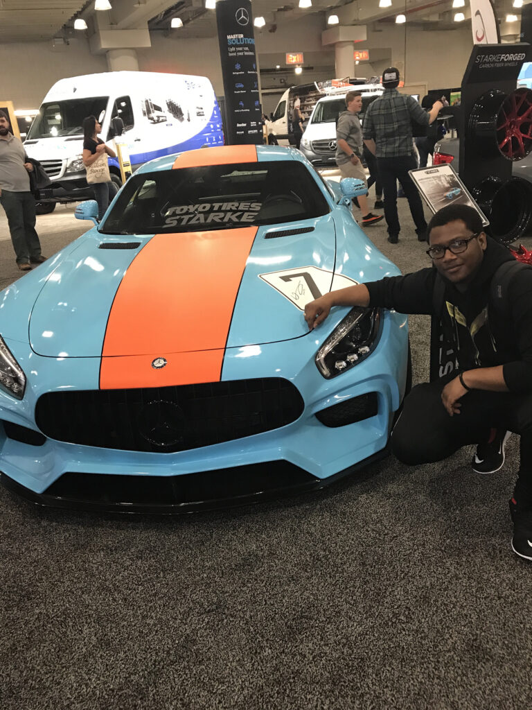 A Car enthusiast posing next to an amg gt at the jacob javits center new york auto show.